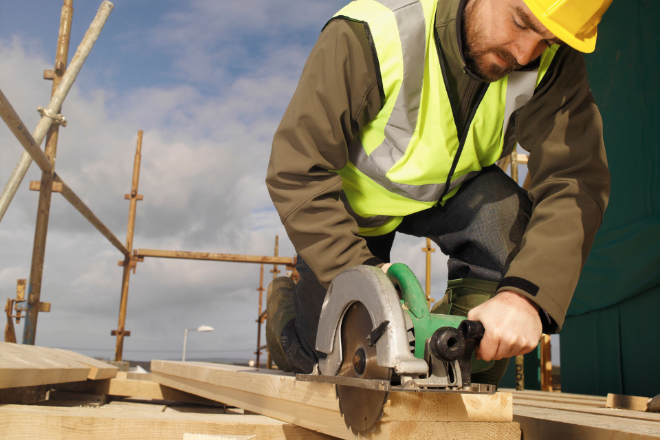 Zimmermann sägt Balken auf Gerüst